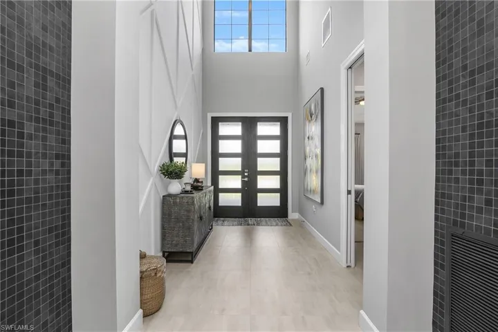 Open and welcoming two story foyer with detailed woodwork & new double door impact entry doors.