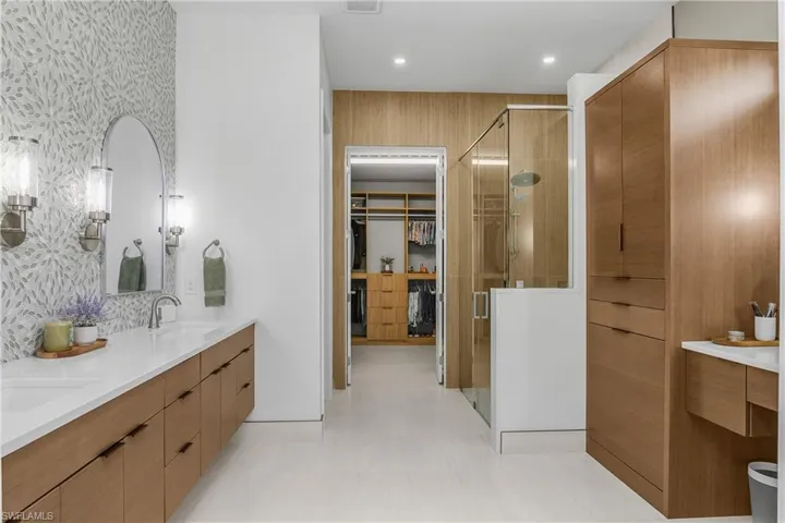 Recently renovated primary bath features glass shower enclosure, new cabinetry, dedicated makeup vanity area, and additional linen storage space.