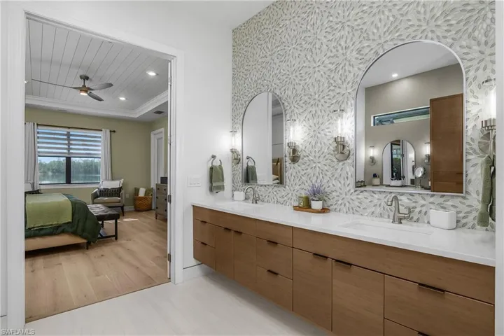 Primary bath includes floating cabinetry, custom tile, dual sinks, and lighted wall sconces.