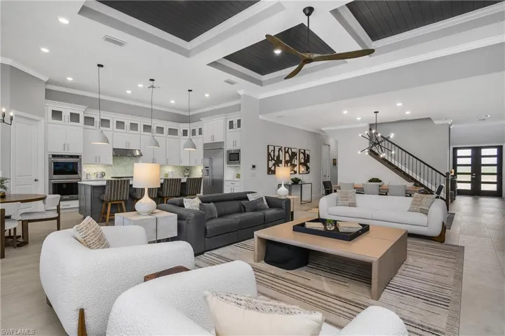 Open Great Room, perfect for entertaining, features high coffered ceilings with tongue and groove wood accent, crown molding, open wood and rod iron staircase.