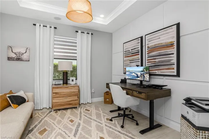 Den/Office with french doors located just off great room. Note the tray ceiling with crown molding and custom wood accent wall.