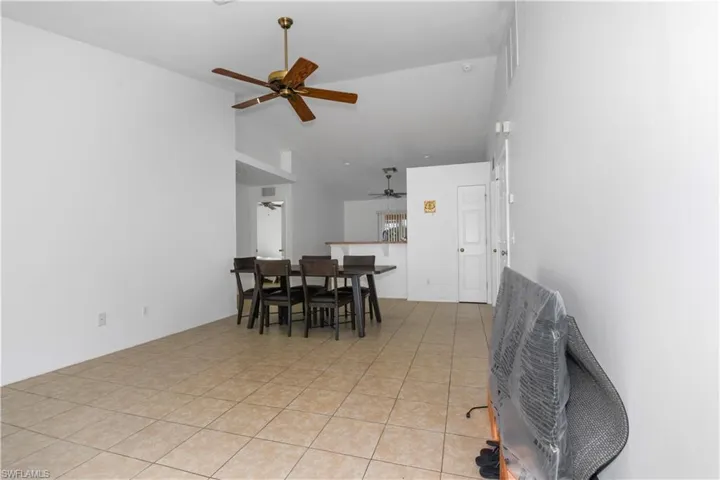 Dining space with a ceiling fan, lofted ceiling, and light tile patterned flooring