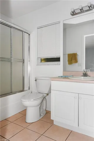 Bathroom featuring vanity, light tile patterned floors, and shower / bath combination with glass door