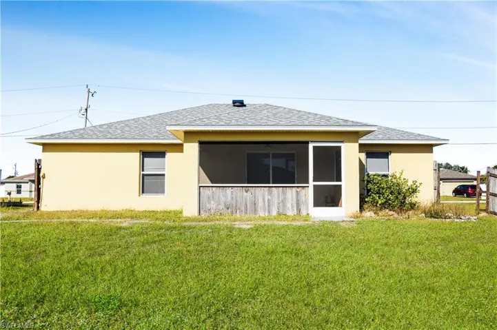 Back of property with roof with shingles, a yard, a sunroom, and stucco siding