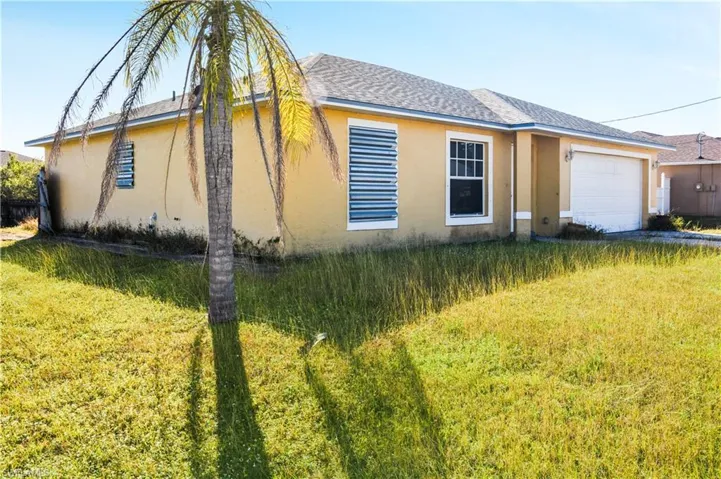 View of front of house featuring stucco siding, a front lawn, an attached garage, and a shingled roof
