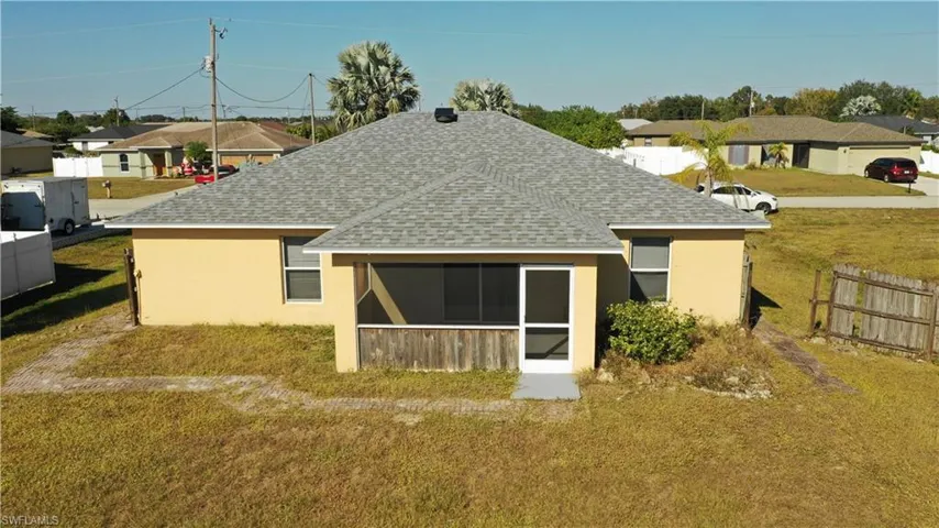 Rear view of house with a shingled roof, a sunroom, stucco siding, and a residential view