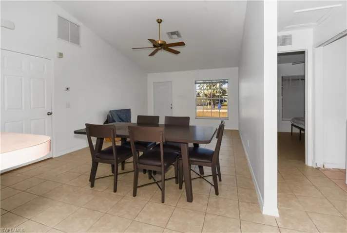 Dining space with light tile patterned flooring, a ceiling fan, and high vaulted ceiling