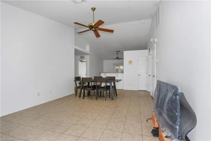 Dining area with ceiling fan, light tile patterned flooring, and high vaulted ceiling