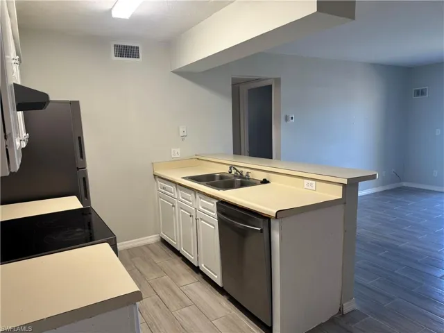 Kitchen with stainless steel fridge, kitchen peninsula, sink, and dishwasher