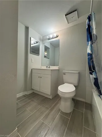 Full bathroom featuring shower / bathtub combination with curtain, vanity, and toilet