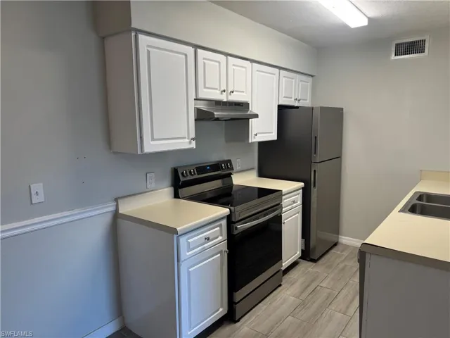 Kitchen with white cabinetry, appliances with stainless steel finishes, and sink