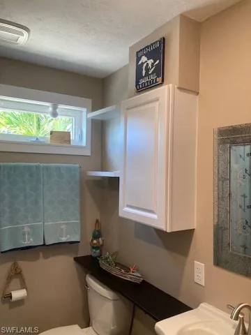Bathroom featuring a sink, a textured ceiling, visible vents, and toilet