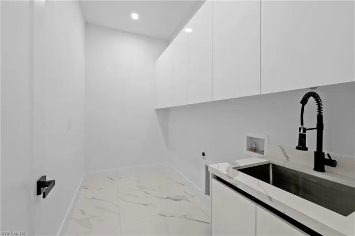Washroom featuring cabinets, hookup for an electric dryer, sink, and washer hookup