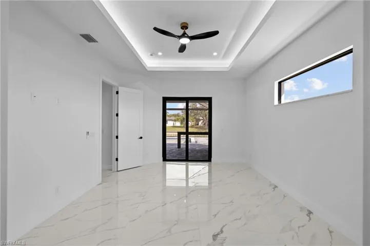 Unfurnished room with ceiling fan and a tray ceiling
