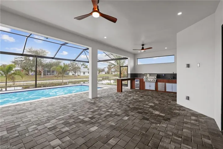 View of pool featuring a water view, a grill, and ceiling fan