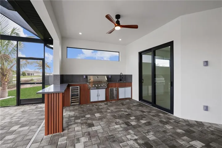 View of patio with an outdoor kitchen, area for grilling, beverage cooler, an outdoor wet bar, and ceiling fan