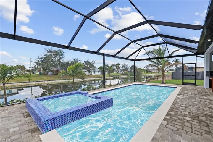 View of pool featuring a water view, an in ground hot tub, a lanai, and a patio area