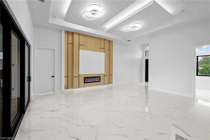 Empty room with a large fireplace and a raised ceiling