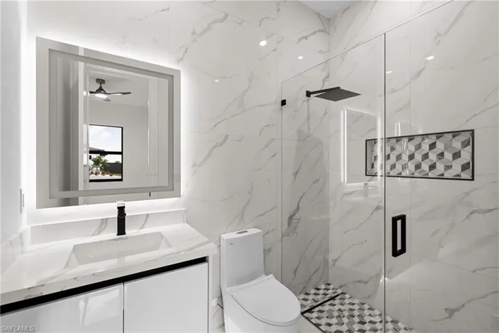 Bathroom with vanity, a shower with door, and toilet