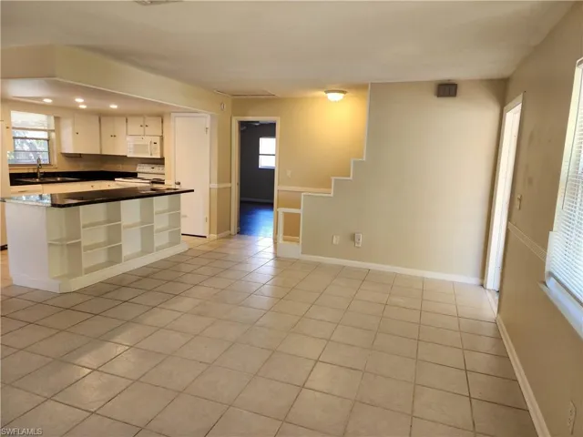 Standing in far corner of living room looking towards kitchen, primary bedroom and entry