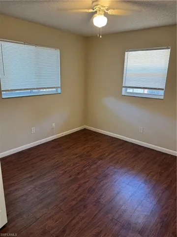 Two large windoslet the light into the primary bedroom. Ceiling fan with light and wood floors