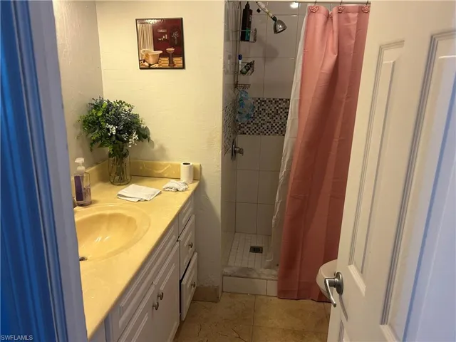 Full bath with vanity, a stall shower, and a textured wall