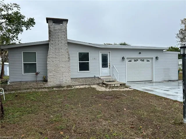 View of front of property featuring an attached garage, driveway, and a chimney