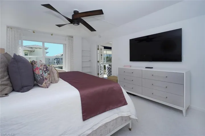 Bedroom featuring light carpet, multiple windows, and a ceiling fan
