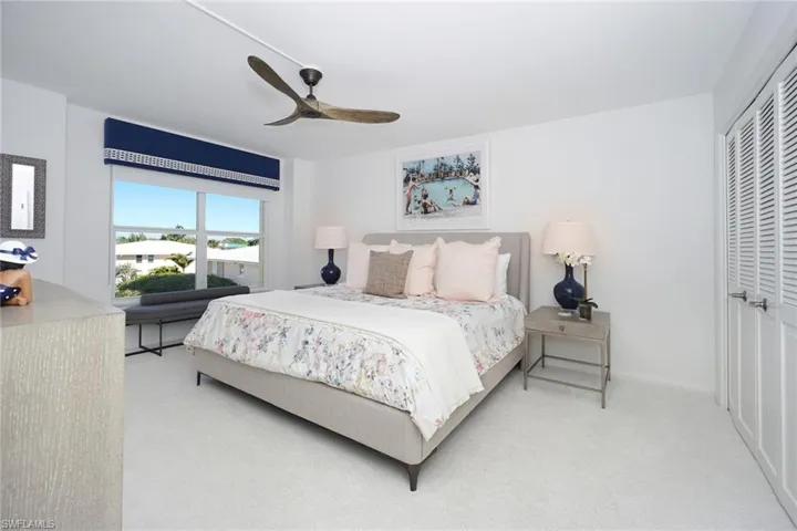 Carpeted bedroom with ceiling fan and a closet