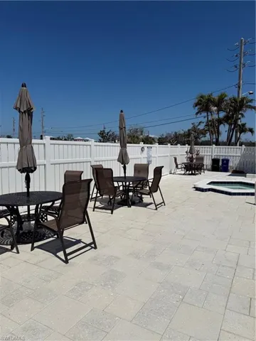 Fenced backyard featuring outdoor dining space, an in-ground hot tub, and a patio area