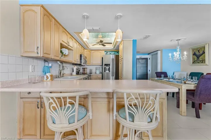 Kitchen featuring decorative light fixtures, a peninsula, light brown cabinets, and light countertops