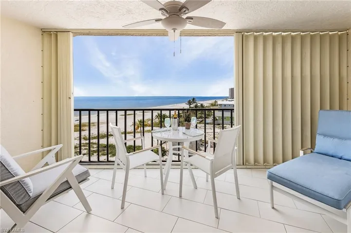 Balcony with a ceiling fan and view of water and beach