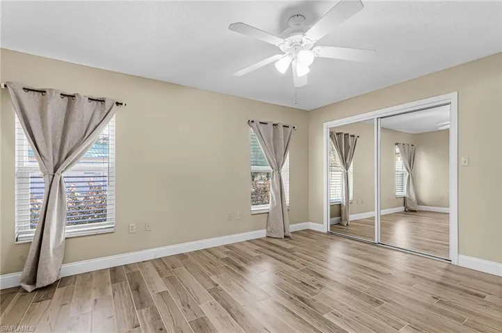 Unfurnished bedroom with wood tiled floors, a closet, ceiling fan, multiple windows, and a textured ceiling
