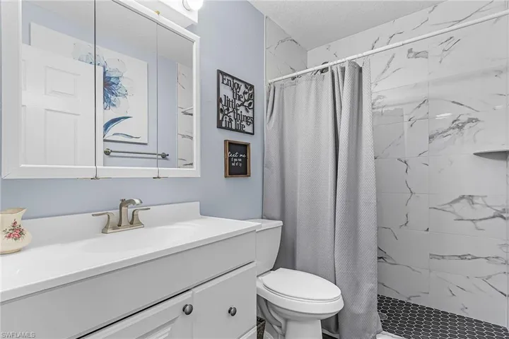 Full bathroom with a shower stall, vanity, and a textured ceiling