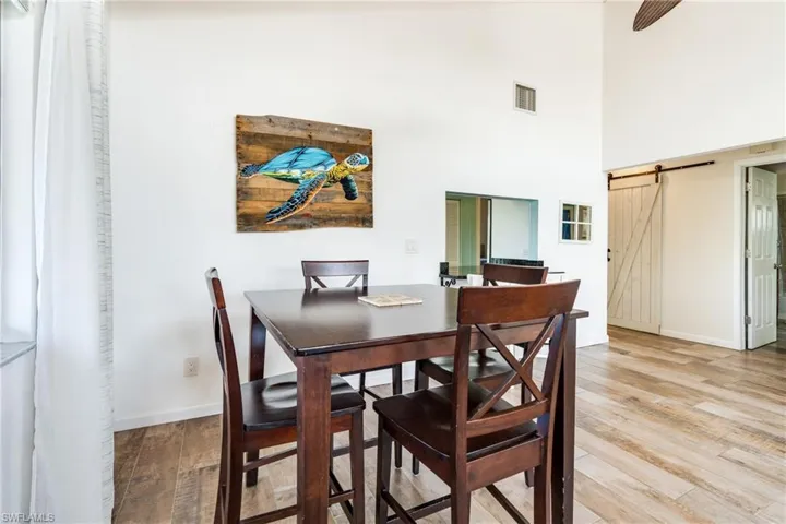 Dining space featuring light wood-type flooring, visible vents, baseboards, and a barn door