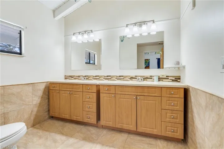 Bathroom with wainscoting, tile walls, toilet, and vanity