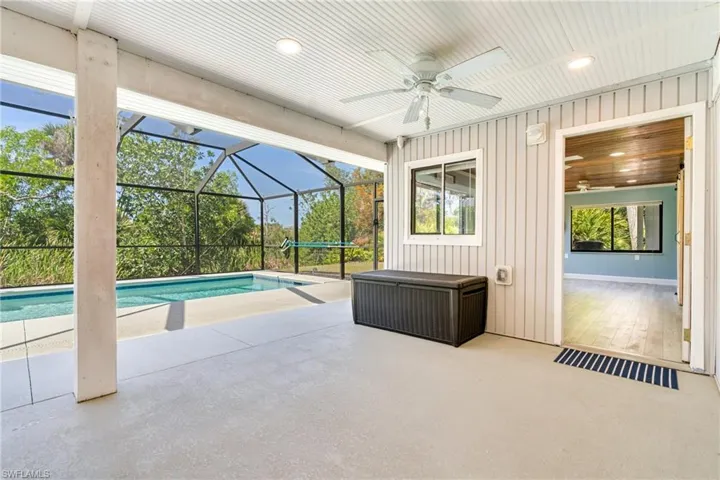 Outdoor pool featuring a patio area, ceiling fan, and glass enclosure