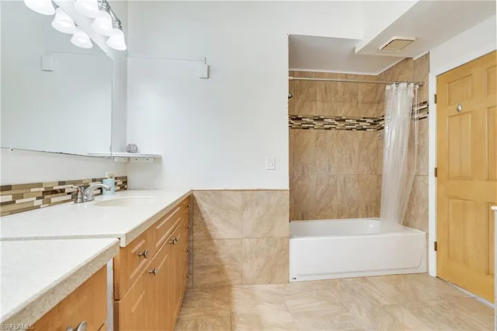 Bathroom featuring shower / bath combo with shower curtain, vanity, and tile walls