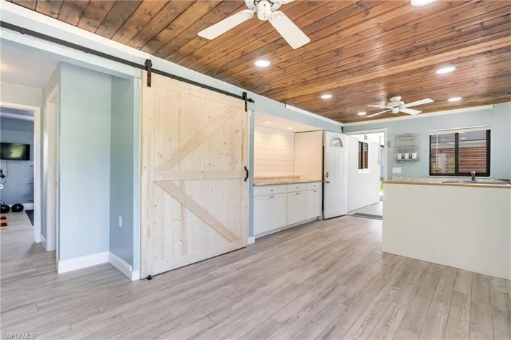 Kitchen featuring a barn door, a ceiling fan, wood ceiling, light wood-style flooring, and recessed lighting