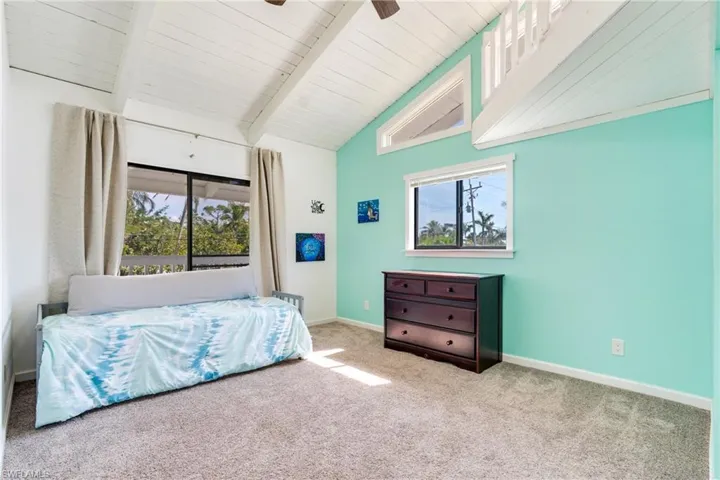 Carpeted bedroom with vaulted ceiling with beams, ceiling fan, and baseboards
