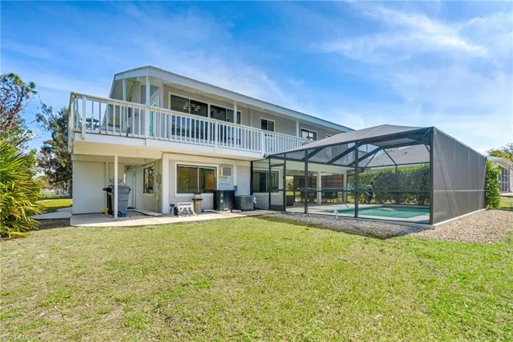 Rear view of property featuring a yard, a patio, central AC unit, a lanai, and an outdoor pool