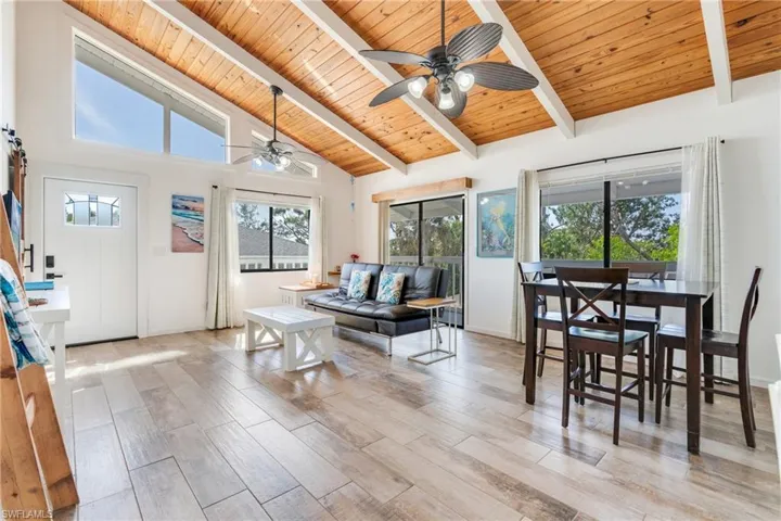 Dining area featuring a ceiling fan, wood ceiling, beamed ceiling, light wood-style floors, and high vaulted ceiling