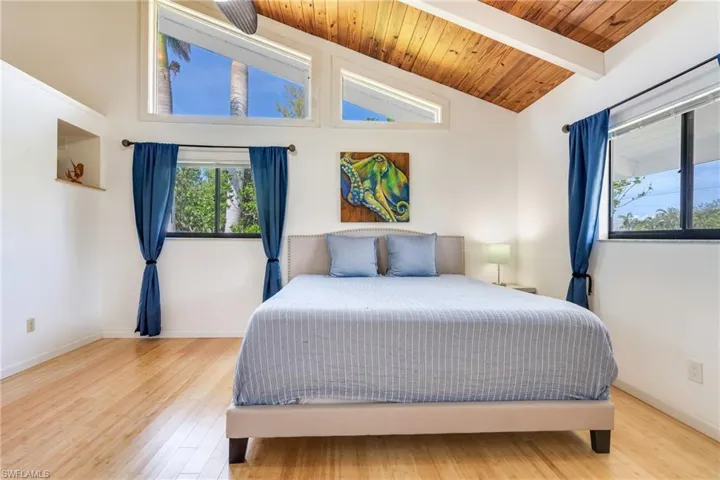 Bedroom with lofted ceiling with beams, wooden ceiling, baseboards, and wood finished floors