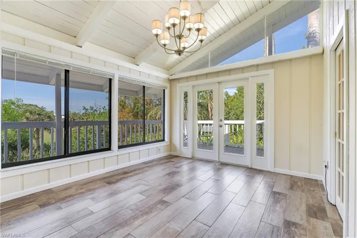 Unfurnished sunroom with a chandelier, a wealth of natural light, french doors, and lofted ceiling with beams