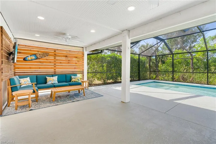 View of pool featuring glass enclosure, an outdoor living space, a ceiling fan, and a patio