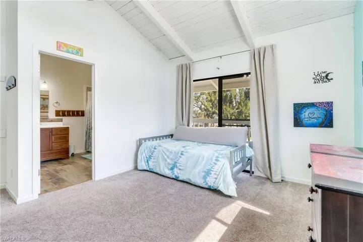Carpeted bedroom featuring vaulted ceiling with beams, baseboards, wooden ceiling, and ensuite bathroom