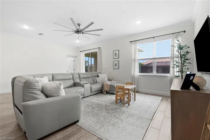 Living room featuring light hardwood / wood-style flooring, ornamental molding, and ceiling fan