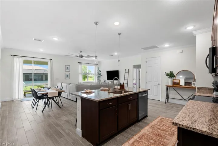 Kitchen featuring light stone counters, appliances with stainless steel finishes, a kitchen island with sink, light wood-type flooring, and sink