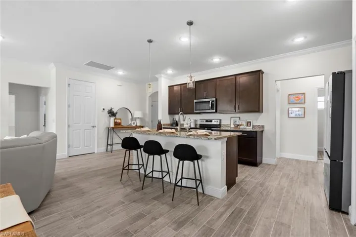 Kitchen featuring light hardwood / wood-style flooring, a kitchen island with sink, stainless steel appliances, and a breakfast bar area