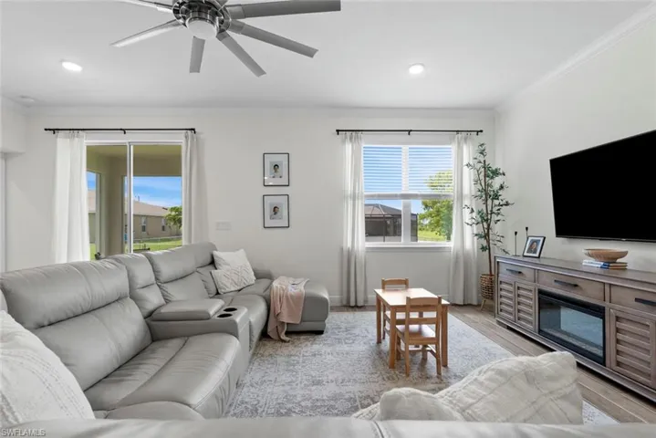 Living room featuring ceiling fan, light wood-type flooring, and crown molding